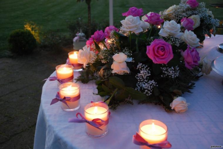 Allestimento con candele e rose per il tavolo della torta nuziale