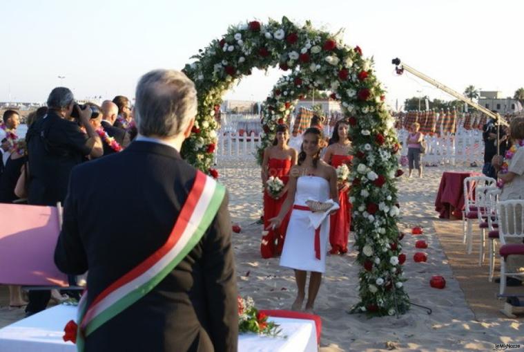 Sposarsi sulla spiaggia sotto un arco di fiori