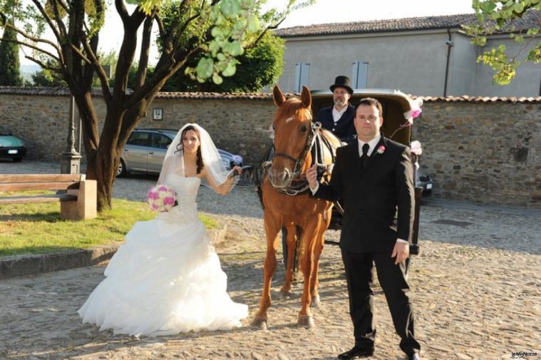 Gli sposi posano con la carrozza per il matrimonio